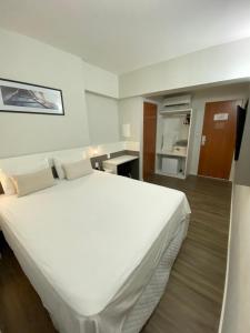 ein großes weißes Bett in einem Hotelzimmer in der Unterkunft It's Hotel in Caratinga