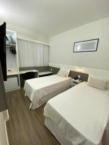 a hotel room with two beds and a tv at IT's Hotel in Caratinga