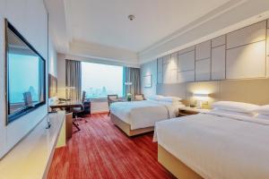 蘇州市にあるルネッサンス ソジョウ ホテルのベッド2台とデスクが備わるホテルルームです。