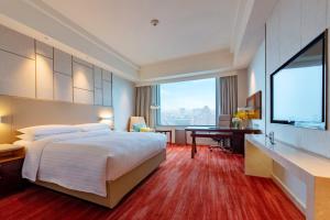 um quarto de hotel com uma cama grande e uma secretária em Renaissance Suzhou Hotel em Suzhou