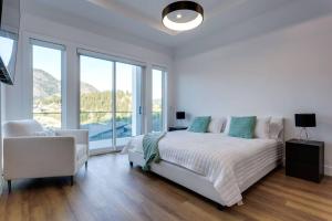a white bedroom with a bed and a chair at Luxury Golf Stay w/Hot Tub in Kelowna