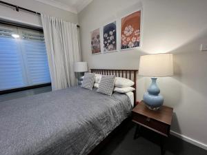 a bedroom with a bed and a lamp on a table at Cosy Merewether Studio - sleeps one in Merewether