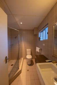 a bathroom with a toilet and a shower and a sink at Imperial Motel in Bowral