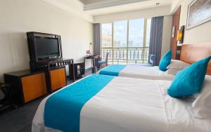 三亜市にあるシェンイ ホリデー ヴィラ ホテルのベッド2台、薄型テレビが備わるホテルルームです。
