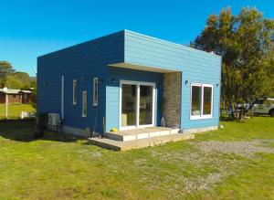 ein kleines blaues Haus auf einem Grasfeld in der Unterkunft Cabañas Maravillas de Quetroleufu in Pucón