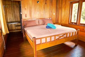 Cama en habitación con paredes de madera en Maratua Guesthouse, en Maratua Atoll