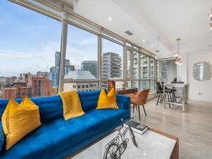 a blue couch in a room with large windows at Boutique Vista Two Bedroom Suite - Toronto's Entertainment District in Toronto