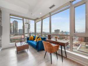 a living room with a blue couch and large windows at Boutique Vista Two Bedroom Suite - Toronto's Entertainment District in Toronto