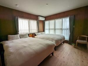 a bedroom with two beds and a chair and windows at Cobaco Ohori - Renovation Vacation rental in Fukuoka