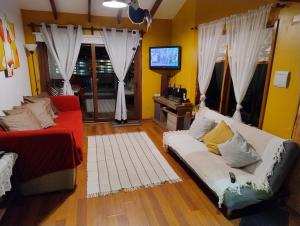 a living room with a couch and a tv at Playa Los Molles , lindo lugar , cómoda cabaña, ideal para descansar , los esperamos 24 7 in Los Molles