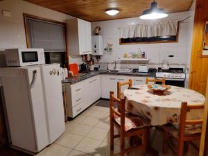 a kitchen with a table and a white refrigerator at playa Los Molles, hermosa playa,te esperamos en cabaña5 in Los Molles