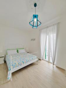 una camera bianca con letto e lampadario pendente di Dimora Acquamarina a Monopoli