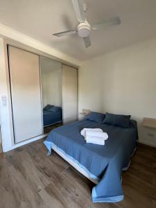 Un dormitorio con una cama azul con toallas. en TERRA - Departamento 2 en Esperanza