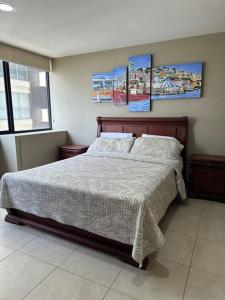 1 dormitorio con 1 cama con 3 cuadros en la pared en Departamento en Puerto Santa Ana, en Guayaquil