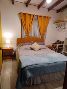 a bedroom with a large bed with yellow curtains at Playa Los Molles , lindo lugar , cómoda cabaña, ideal para descansar , los esperamos 24 7 in Los Molles