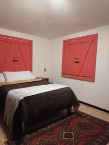 um quarto com portas vermelhas e uma cama com um tapete em habitación en medio de la naturaleza em Zacatlán