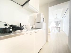 uma cozinha com armários brancos e um frigorífico branco em アネックス日本橋東401 em Osaka