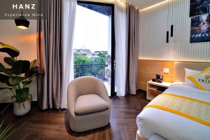 a bedroom with a bed and a chair and a window at HANZ Premium Friday Hotel in Ho Chi Minh City