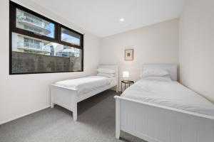 2 bedden in een witte kamer met een raam bij Spacious 3-Bed Home with Alfresco Dining Patio in Canberra