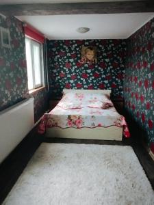 een kleine slaapkamer met een bed met bloemenbehang bij Vila la 4 Turturici in Năvodari