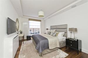 Habitación blanca con cama y TV en Large Super Penthouse Park Lane Opposite Hyde Park Sleeps 12, en Londres