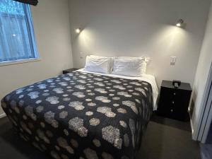 a bedroom with a bed with a black and white comforter at Shelby Motor Lodge in Invercargill