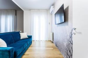 een woonkamer met een blauwe bank en een televisie bij La Bella Vita - La Terrazza in Sottomarina
