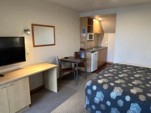 um quarto de hotel com uma cama, uma secretária e uma cozinha em Shelby Motor Lodge em Invercargill