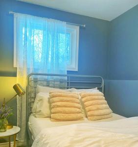 a blue bedroom with a bed with pillows and a window at Premier Affordable Barrie Suite in Barrie