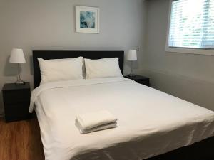 um quarto com uma grande cama branca e 2 candeeiros em Edmonds Home em Burnaby