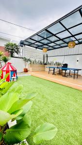 eine Terrasse mit einem grünen Garten und 2 Picknicktischen in der Unterkunft Villa BaHegia in Cikeruh