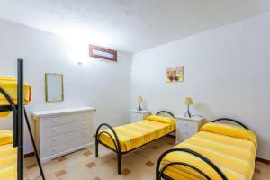two beds in a room with yellow sheets at Comino Alto Agriturismo e Appartamenti in Capo Comino