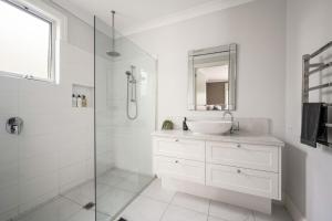 ein weißes Bad mit einem Waschbecken und einer Dusche in der Unterkunft The Banks in Beechworth