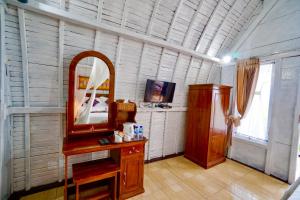 ein Badezimmer mit einem Spiegel und einem Waschtisch sowie einem TV in der Unterkunft Hotra Hill Cottage in Nusa Penida