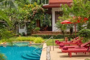 un resort con piscina con sedie rosse e ombrellone di Villa Tropical Bliss Luxury Estate a Nathon Bay