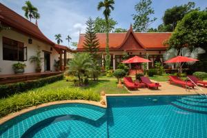 una piscina di fronte a una casa con sedie e ombrelloni di Villa Tropical Bliss Luxury Estate a Nathon Bay