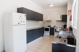 uma cozinha com armários azuis e um frigorífico branco em 140 Ghuznee Hostel em Wellington