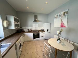 een keuken met een tafel en een kleine tafel met stoelen bij 5 Min Walk to the Best Beach! Lovely 3 Bedroom Charming Cottage! - Great Location - FREE Parking - Fast WiFi - Smart TV - sleeps up to 6! Close to Bournemouth & Poole Town Centre & Sandbanks in Bournemouth