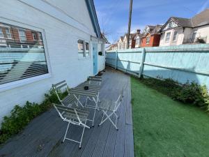 three chairs and a table on a deck at 5 Min Walk to the Best Beach! Lovely 3 Bedroom Charming Cottage! - Great Location - FREE Parking - Fast WiFi - Smart TV - sleeps up to 6! Close to Bournemouth & Poole Town Centre & Sandbanks in Bournemouth