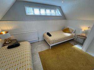 a attic room with two beds and a window at 5 Min Walk to the Best Beach! Lovely 3 Bedroom Charming Cottage! - Great Location - FREE Parking - Fast WiFi - Smart TV - sleeps up to 6! Close to Bournemouth & Poole Town Centre & Sandbanks in Bournemouth