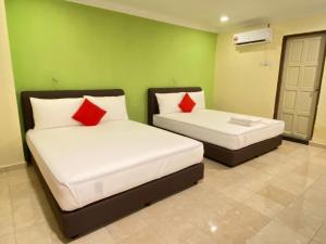 2 letti in una camera con pareti verdi e cuscini rossi di HOTEL SAHARA INN TANJUNG MALIM a Kampong Chabang