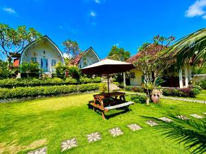 a garden with an umbrella and a bench in the grass at Hotra Hill Cottage in Nusa Penida