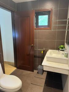 een badkamer met een toilet, een wastafel en een raam bij Tamarind Villa in Kuah