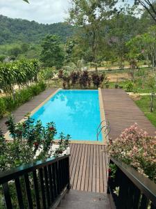 een groot blauw zwembad met een houten terras bij Tamarind Villa in Kuah