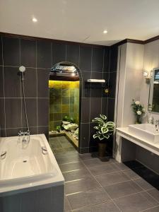 een badkamer met een bad, 2 wastafels en een douche bij Tamarind Villa in Kuah