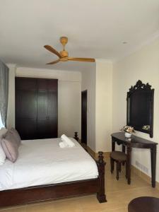 een slaapkamer met een bed en een bureau met een plafondventilator bij Tamarind Villa in Kuah