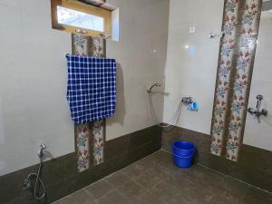 een badkamer met een douche en een blauwe emmer bij Kumaon Lake's Home stay in Nainital