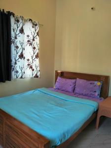 sypialnia z łóżkiem z niebieską pościelą i oknem w obiekcie White bungalow w mieście Madikeri