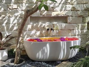 a white tub filled with flowers next to a stone wall at ONAYA Bali Resort - Adults Only in Uluwatu