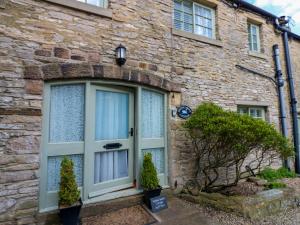 a stone house with a large glass door at White Swan Cottage in Leyburn